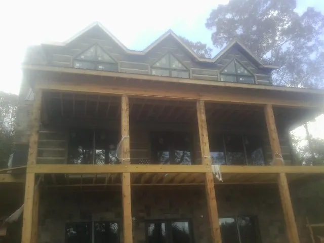 Dormers and porch framing on a large log home under construction — Roof Coating work by our crew in Nampa