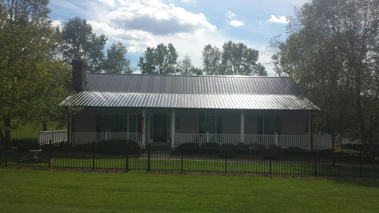 Gray metal roof on a brick ranch with a full width front porch — Gutter Guard Installation work by our crew in Nampa