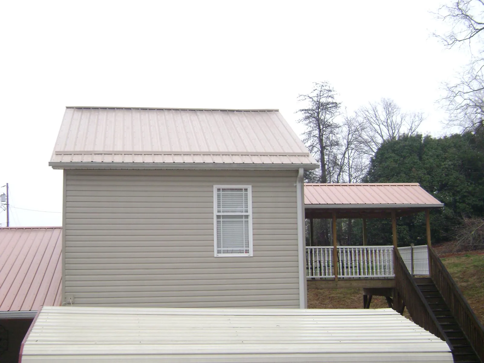 Tan metal roofs on a two story addition and attached porch, from a Roof Replacement job in Nampa