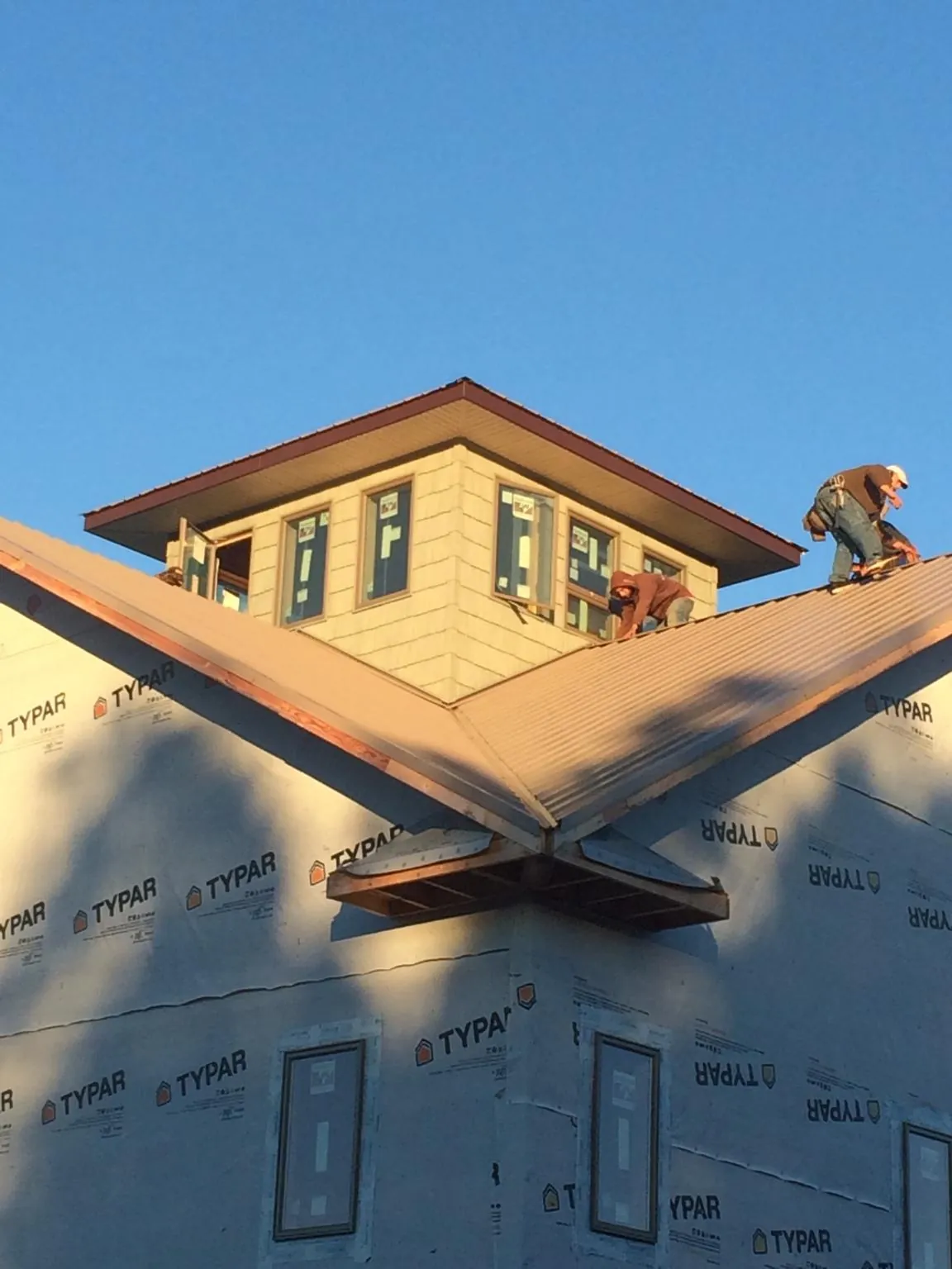 Roofers working around a rooftop cupola on a new metal roof at sunset — Roof Waterproofing in Nampa by Roofing Brothers